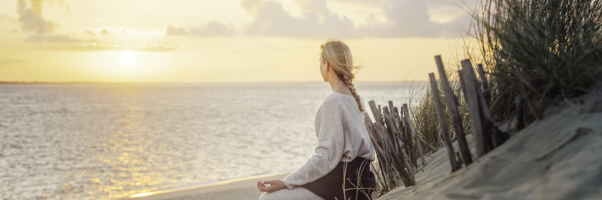 Frau sitz am Strand von Sylt und meditiert